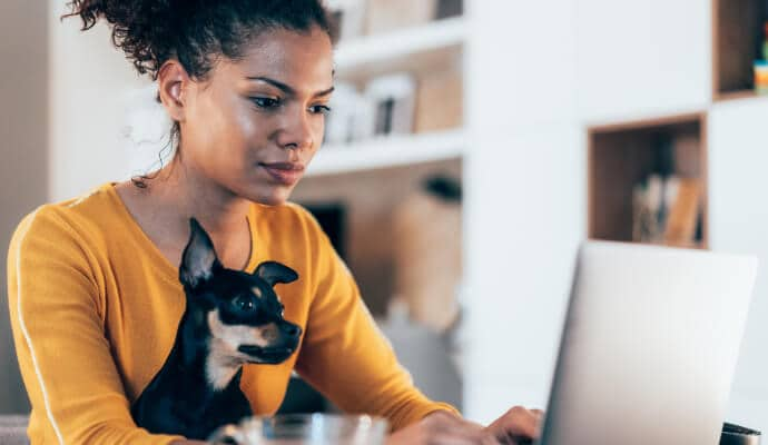 Mujer que utiliza el portátil con un perro sentado en su regazo