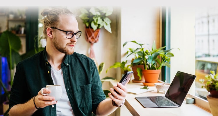 Hombre que sostiene una taza y un teléfono móvil