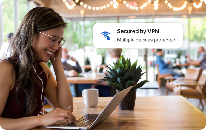 Mujer en una cafetería riendo frente a la pantalla de un portátil