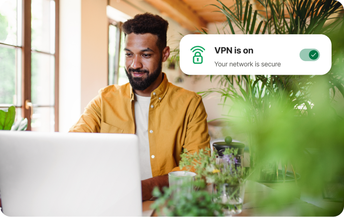 Hombre rodeado de plantas sonriendo frente a un portátil